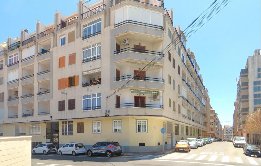 a tall building with cars parked in front of it at Stunning Apartment In Torrevieja With 2 Bedrooms, Wifi And Outdoor Swimming Pool in Torrevieja