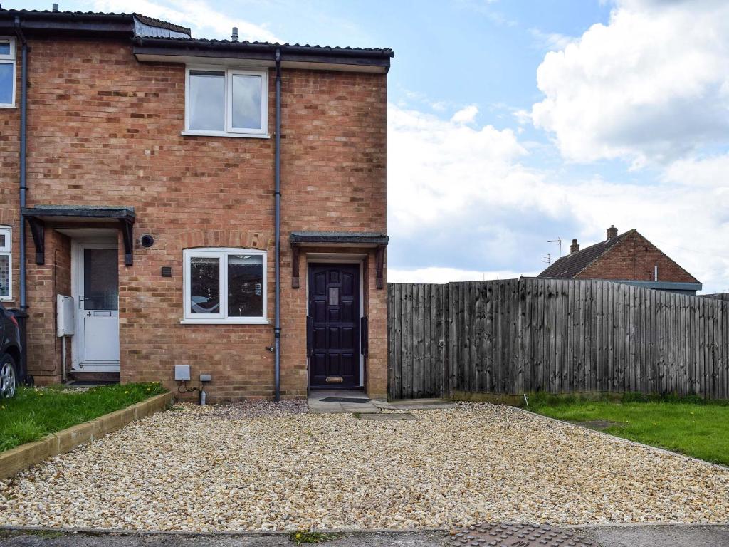 a brick house with a wooden fence at Racing Retreat in Towcester