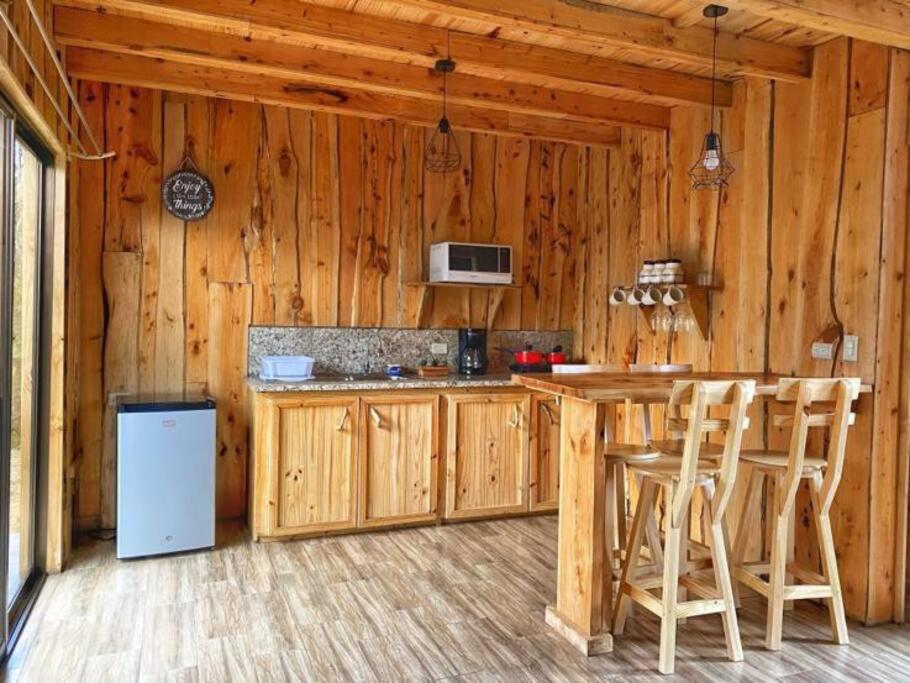 a kitchen with a table and chairs in a cabin at Sinà-Poas Green Chalets in Fraijanes
