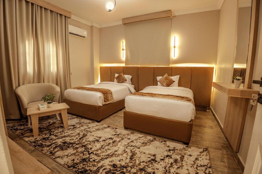 um quarto de hotel com duas camas e uma cadeira em Golden House no Cairo