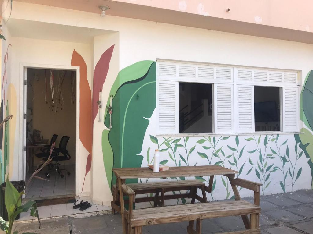 a patio with a table and a wall with a window at Maré Hostel Itapuã in Salvador