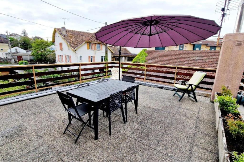 een tafel en stoelen met een paarse parasol op een balkon bij L'Amelia in Thonon-les-Bains