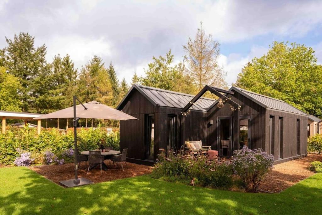 un cobertizo negro con un paraguas en un patio en Lagom I Tiny House en Epe