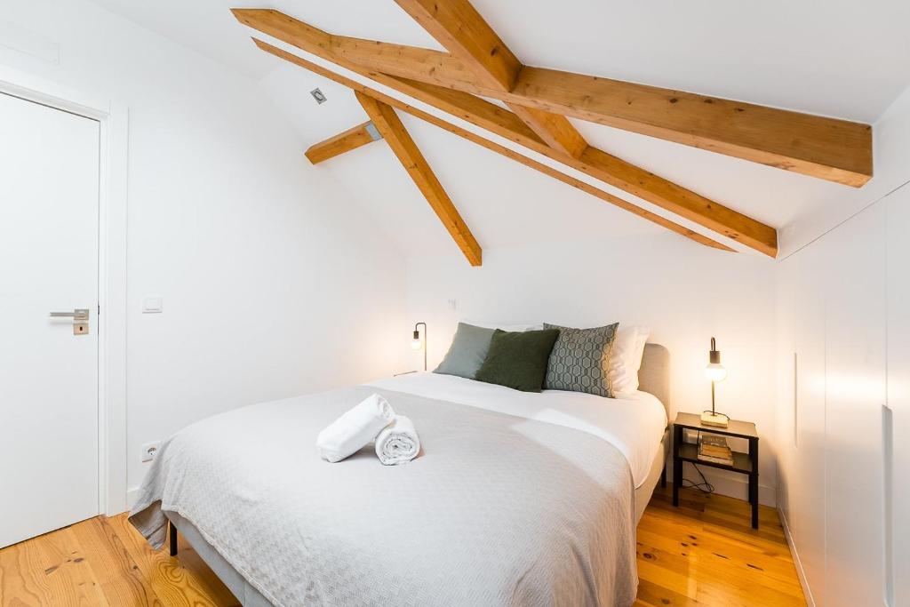 a bedroom with a large white bed with wooden ceilings at GuestReady - Freixo Paradise view in Porto