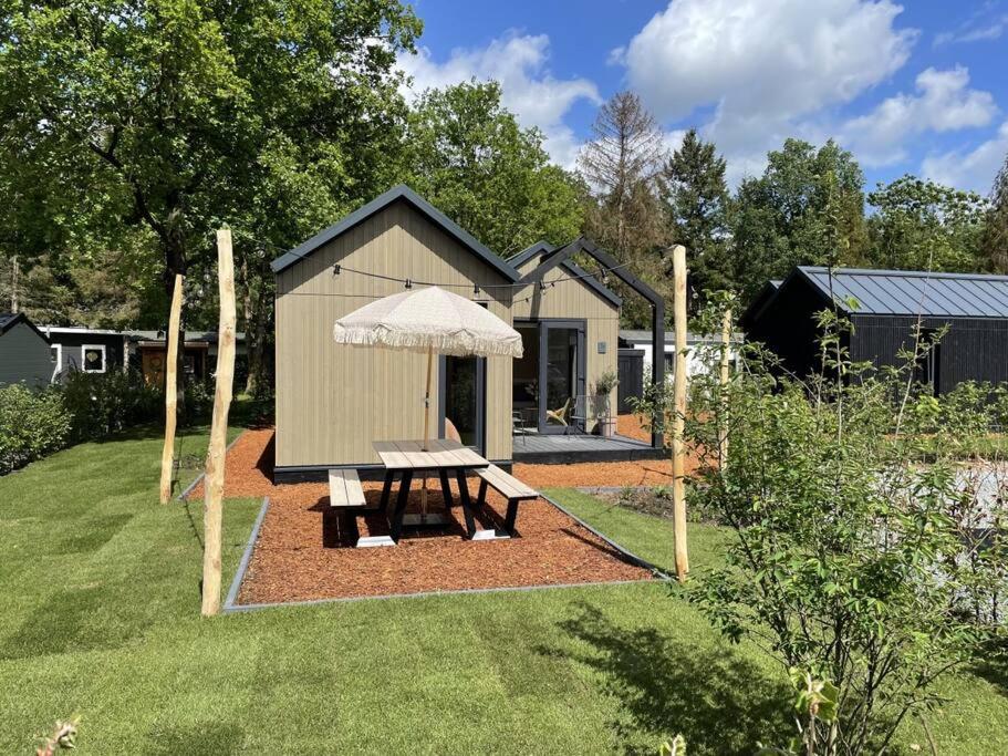 a shed with a picnic table and an umbrella at WØUD Tiny House in Epe