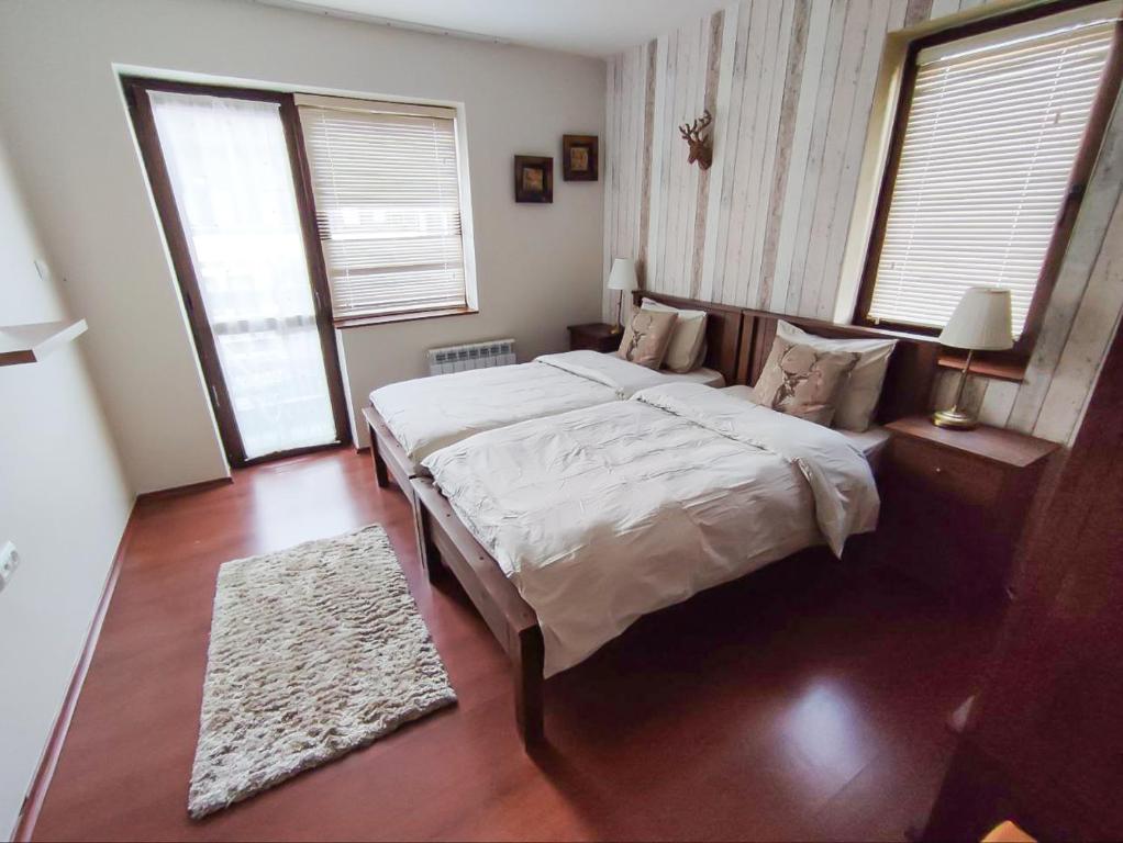 een slaapkamer met een groot bed en 2 ramen bij GALA Apartment in Bansko