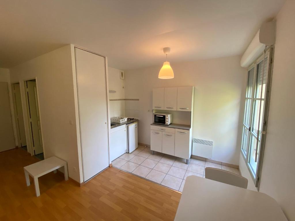 eine Küche mit weißen Schränken sowie einem Tisch und Stühlen in der Unterkunft Appartement moderne avec parking in Blois
