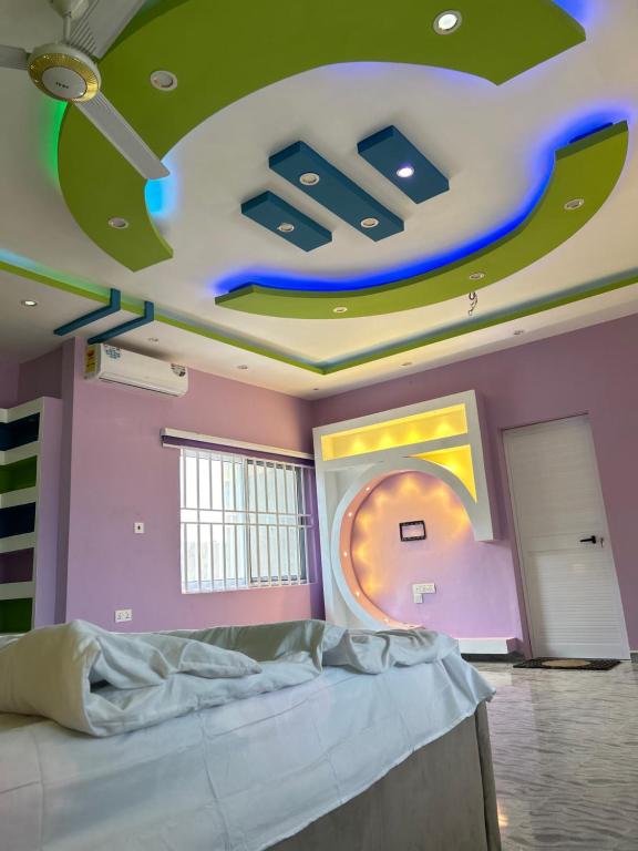 Regitton Hotel في Denu: غرفة بسرير وسقف عليها لوحة