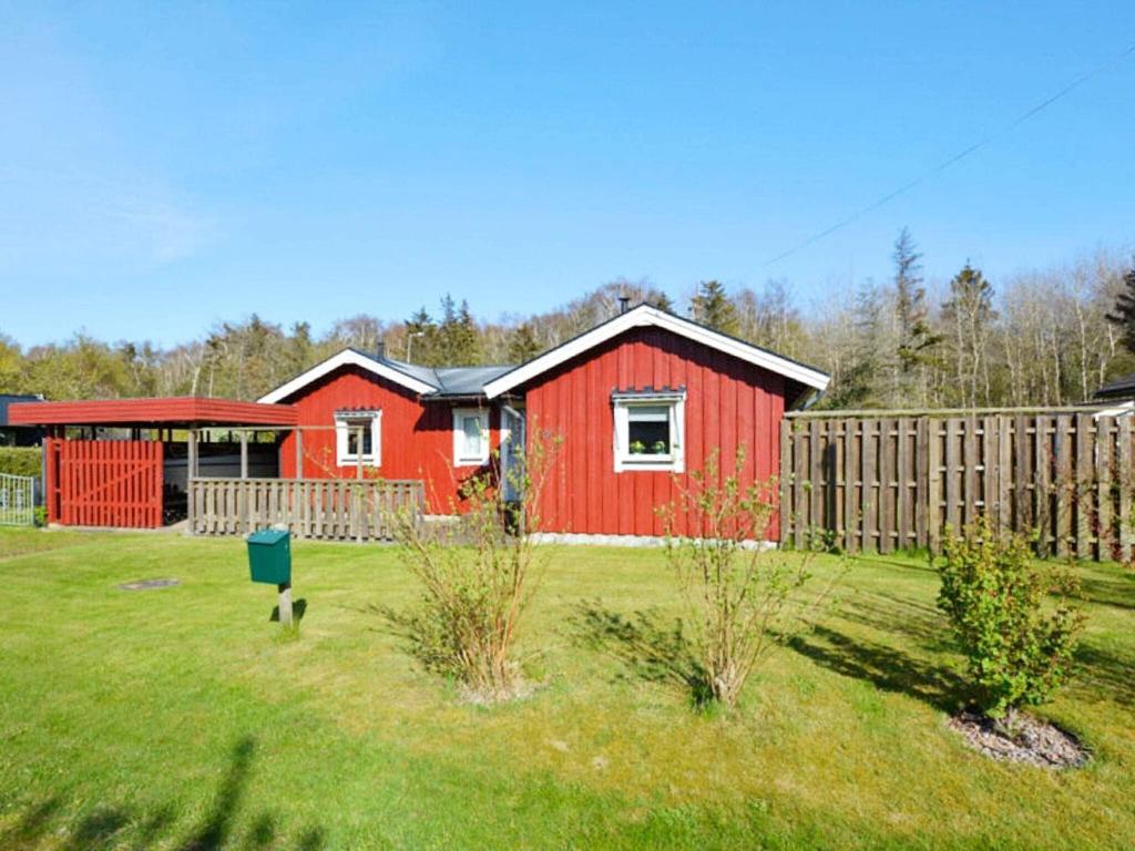 ein rotes Haus in einem Garten mit einem Zaun in der Unterkunft Holiday home LAHOLM XV in Laholm