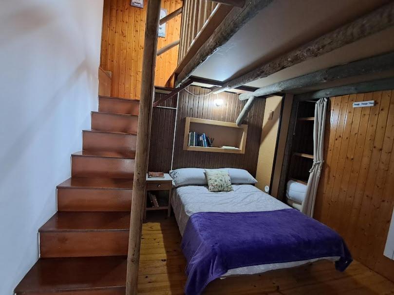 a bedroom with a bed and stairs in a room at La Casa de las rocas - Ribeira Sacra in Rubiacós