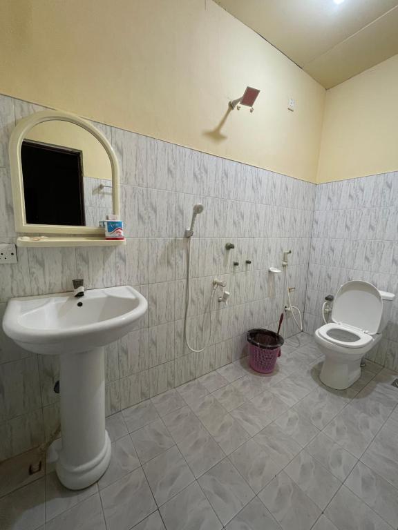 een badkamer met een wastafel, een toilet en een spiegel bij Romance in Bey in Arugam Bay