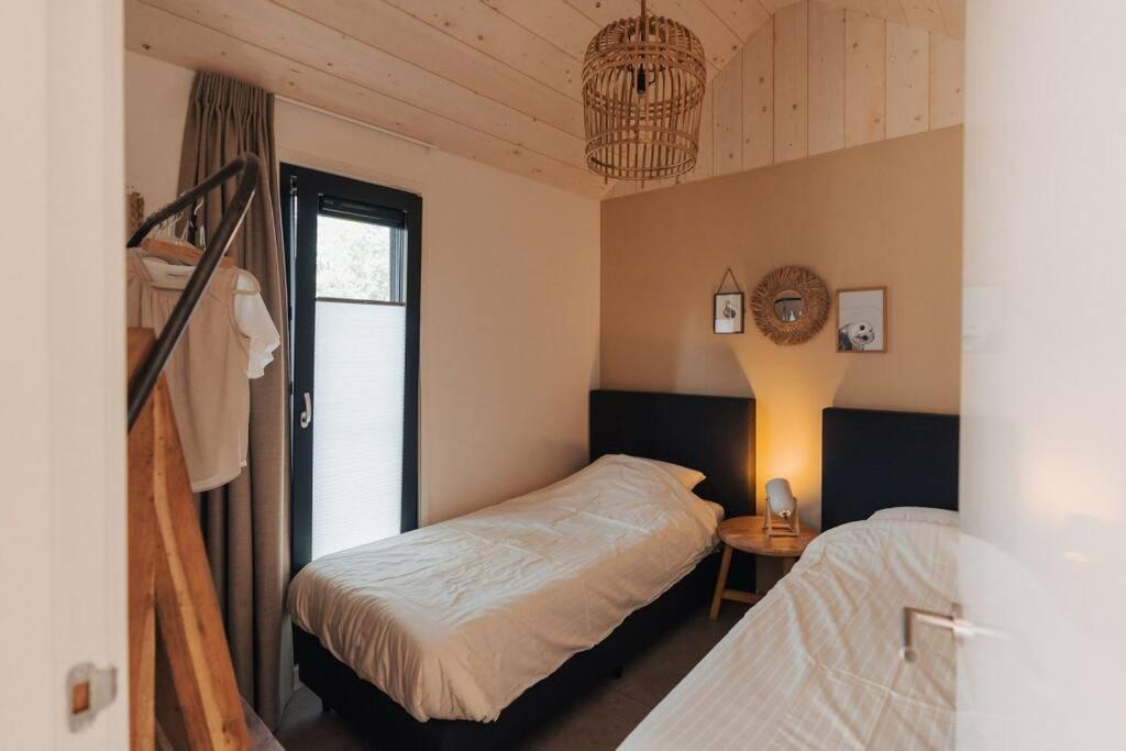 una camera da letto con due letti e una finestra di Kos I Tiny house met grote tuin a Epe
