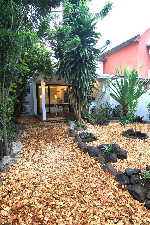 a yard with a house with a pile of leaves at Studio Kaza Blanka - Saint Leu - Réunion in Saint-Leu