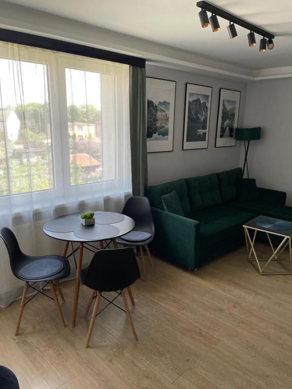 a living room with a green couch and a table at Apartament Zeromskiego in Ostróda