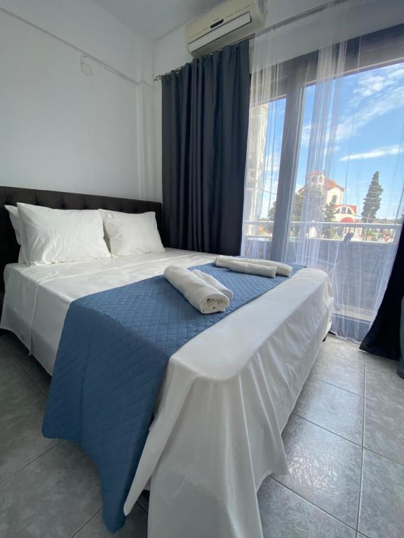 a bedroom with a bed with a blue blanket and a window at Uka apartment in Nea Iraklia
