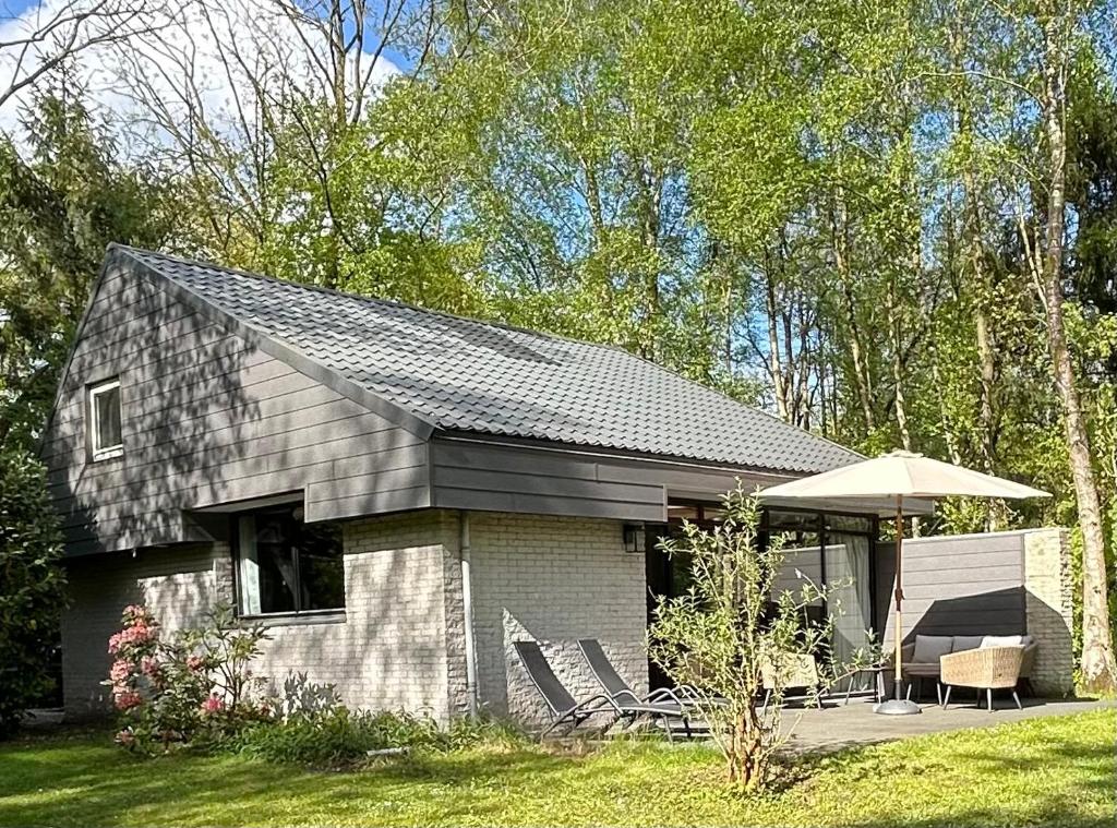 een klein huis met een veranda en een paraplu bij Vrijstaande luxe vakantiewoning met grote tuin, veel privacy en prachtige natuur in Geesbrug