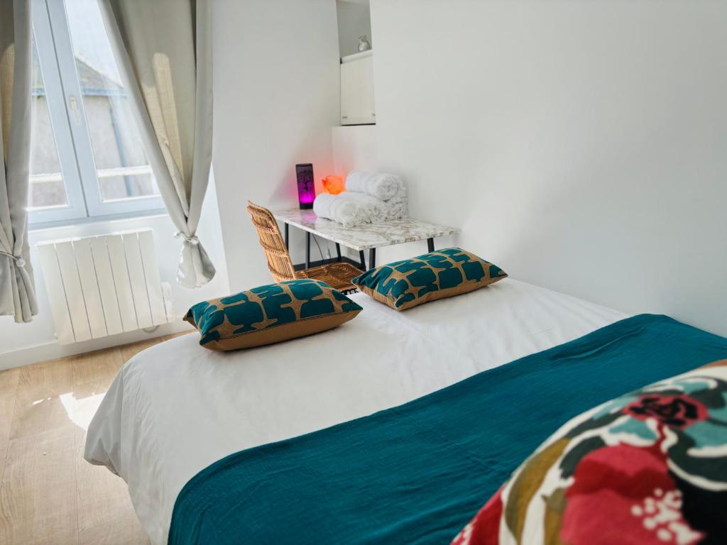 a bedroom with a bed with two pillows and a table at T2 de 30m2 quartier merville à Lorient in Lorient