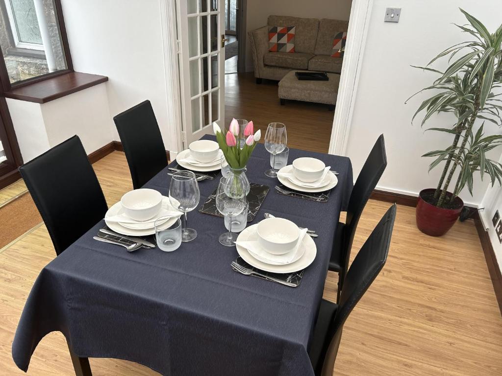 uma mesa de jantar com uma toalha de mesa azul e pratos e copos em House in Stoneywood Dyce em Aberdeen