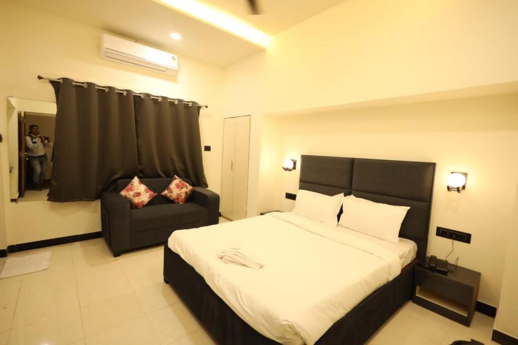 - une chambre avec un grand lit et une chaise dans l'établissement Hotel Parashar Palm, à Nagpur