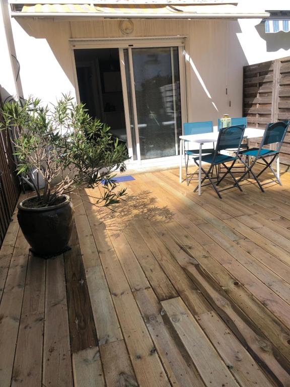 a patio with a table and chairs on a wooden floor at KER HEDWIGE in Carnac