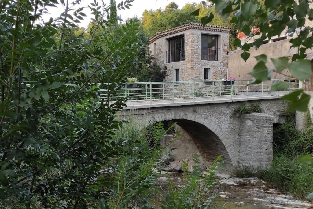 eine Brücke über einen Fluss mit einem Gebäude darauf in der Unterkunft Maison en Drôme provençale in Eygaliers