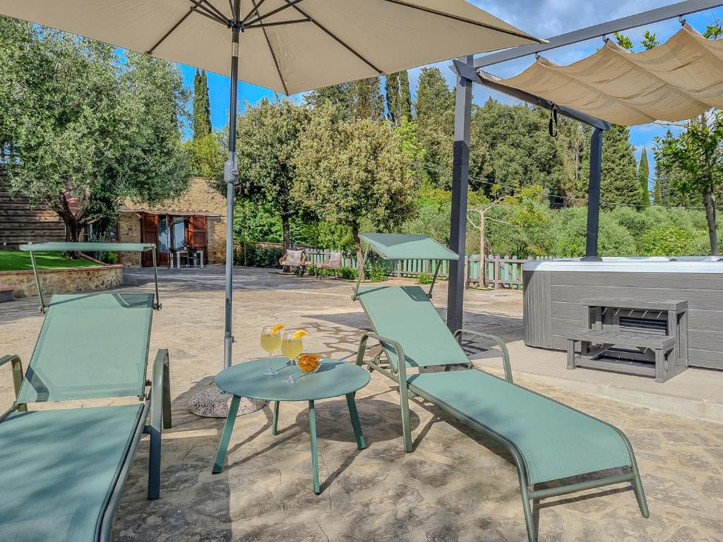 eine Terrasse mit 2 Stühlen, einem Tisch und einem Sonnenschirm in der Unterkunft Casa Iris - Home In the heart of Tuscany & jacuzzi in Bibbiano