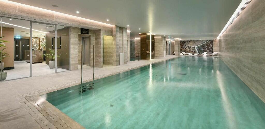 a large swimming pool in a building with a pool at Luxury City Retreat - 1 Bed Fully Equipped in London