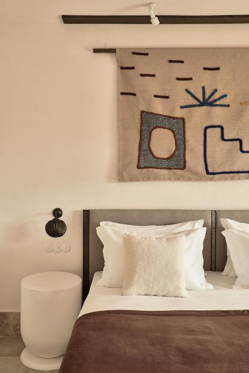 a bed with white pillows and a picture on the wall at Parilio, a Member of Design Hotels in Naousa