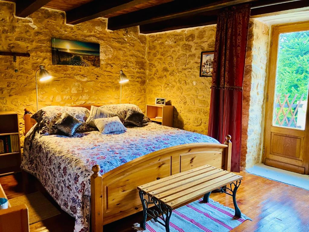 een slaapkamer met een bed en een houten bank bij Maison de Montfort in Vitrac