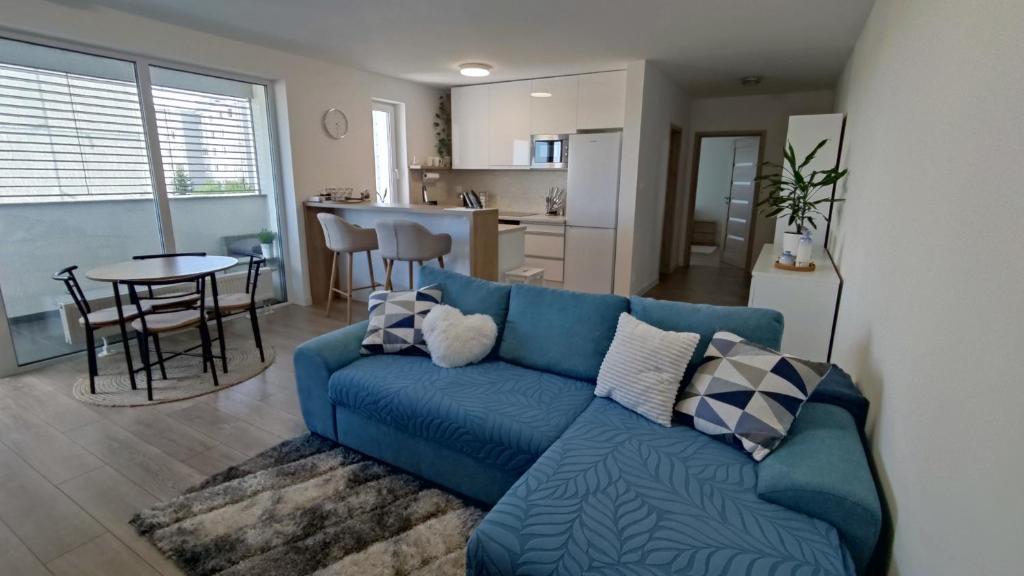 sala de estar con sofá azul y cocina en Apartmán Martina, en Trebišov