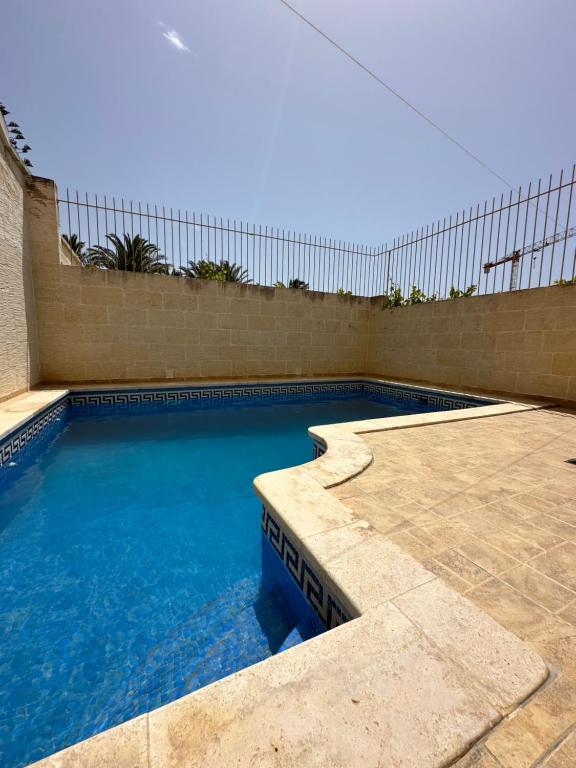 a swimming pool with blue water and a fence at Nawrat Farmhouse in Għarb