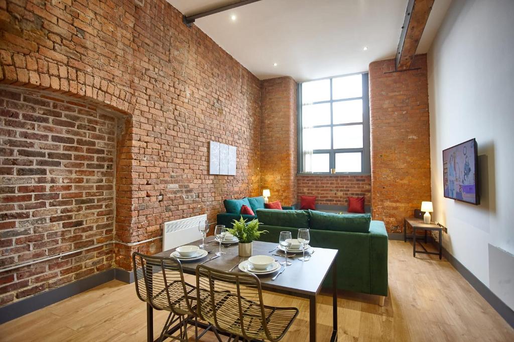 un soggiorno con divano verde e parete in mattoni di The Ruby Suite a Manchester