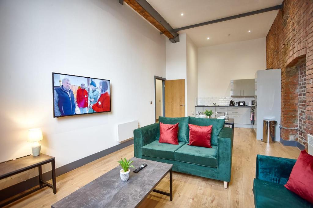 un soggiorno con divano verde e cuscini rossi di The Ruby Suite a Manchester