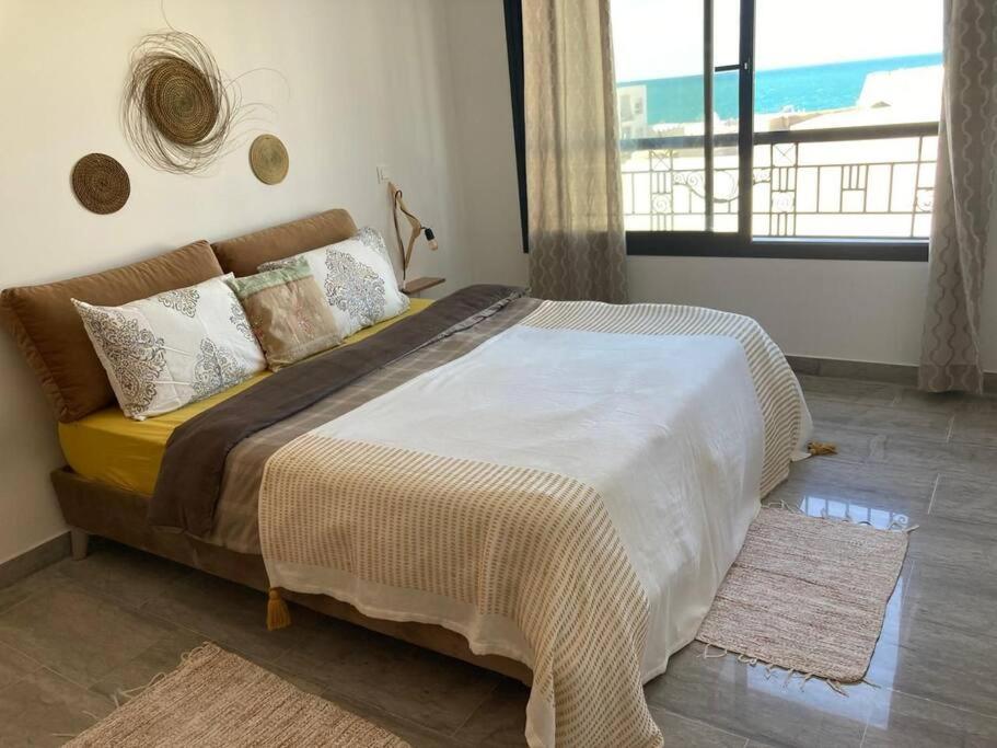 a bedroom with a large bed with a view of the ocean at émeraude au coeur de la marsa plage in La Marsa