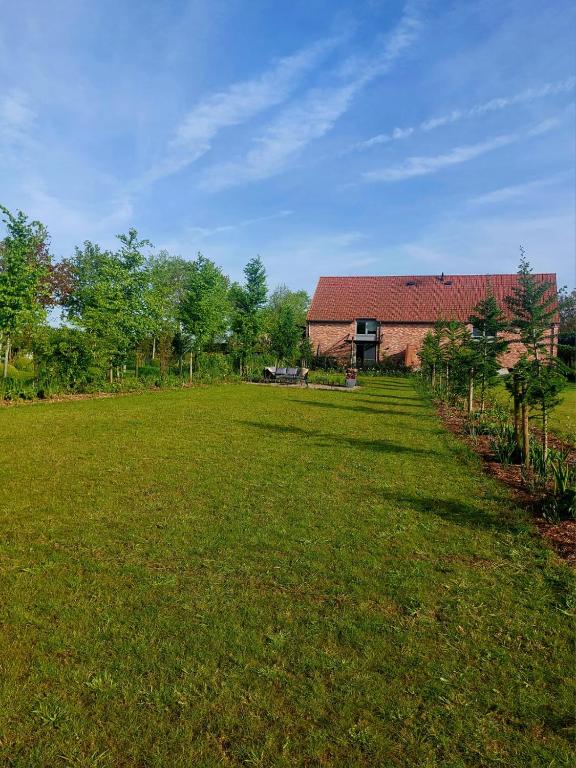 a large grass field with a building in the background at De Weldoeninge in Wingene