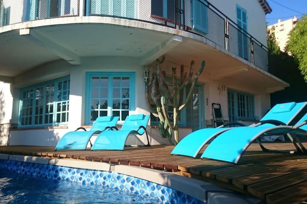 eine Terrasse mit blauen Stühlen neben einem Pool in der Unterkunft Villa de charme 5 pièces vue mer in Antibes