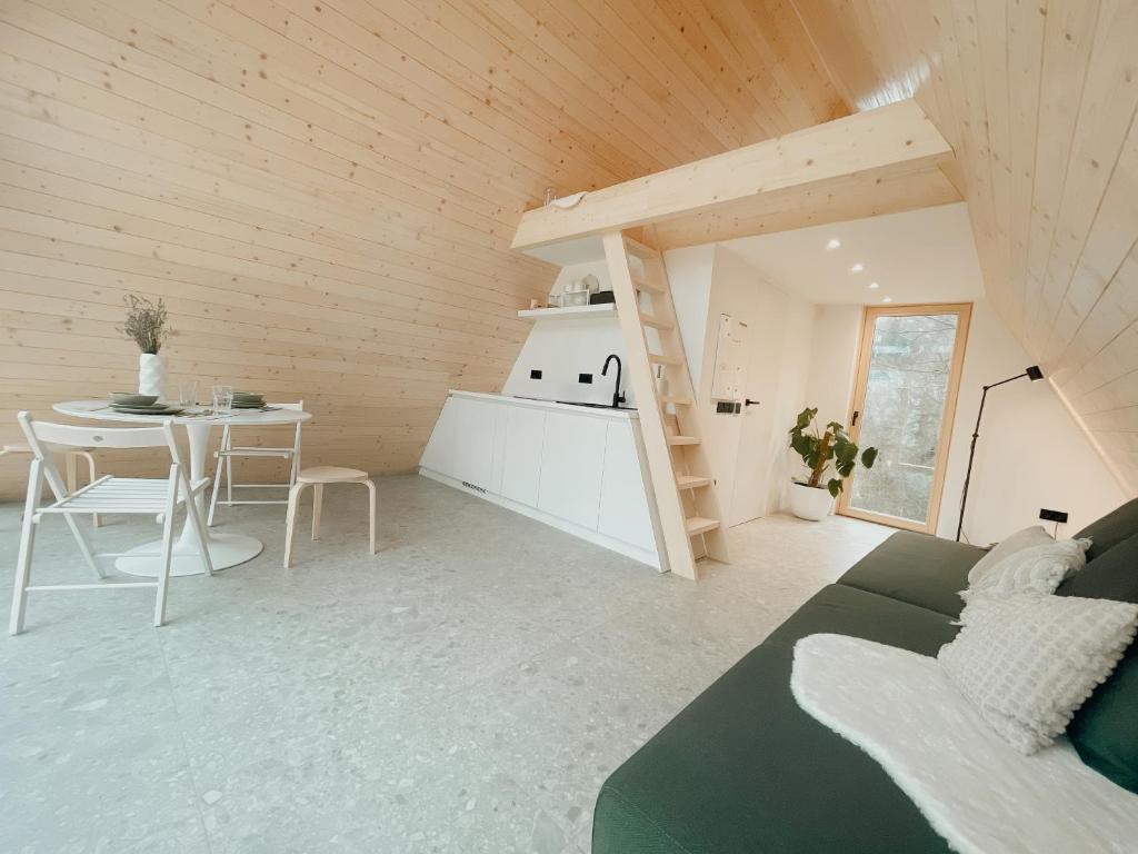 Il dispose d'une cuisine et d'un salon avec un canapé et une table. dans l'établissement A-frame Forest Nest, à Cerklje na Gorenjskem