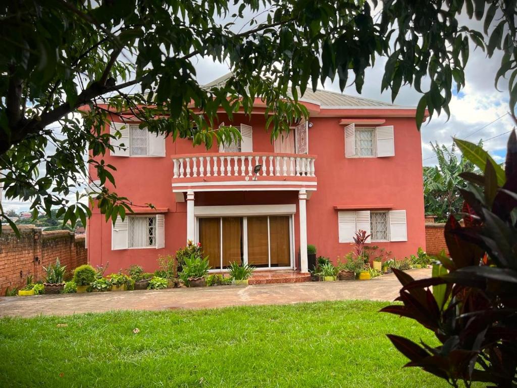 a red house with a balcony and a yard at Résidence Tianay in Antananarivo