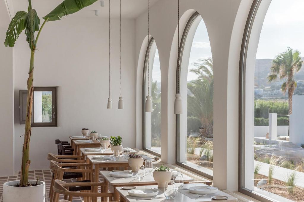 a dining room with tables and chairs and large windows at Parilio, a Member of Design Hotels in Naousa