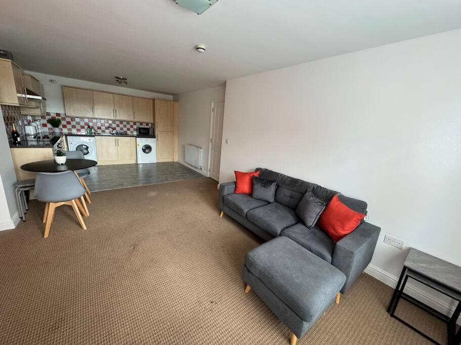 uma sala de estar com um sofá, uma mesa e uma cozinha em Curwen Apartment em Workington