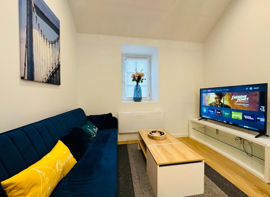 een woonkamer met een blauwe bank en een tv bij Duplex 29 tout inclus in Quimper