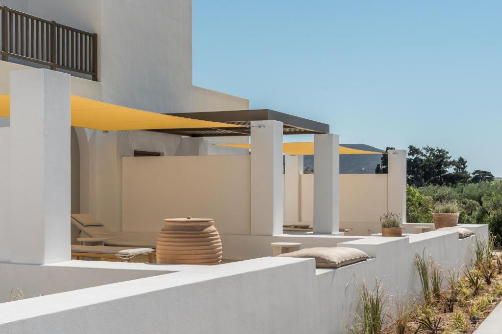 a white house with a patio with a yellow umbrella at Parilio, a Member of Design Hotels in Naousa