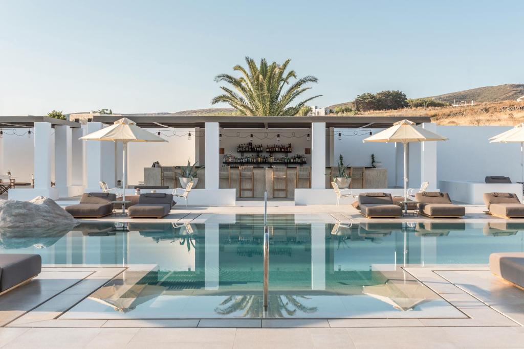 a swimming pool with lounge chairs and umbrellas at Parilio, a Member of Design Hotels in Naousa
