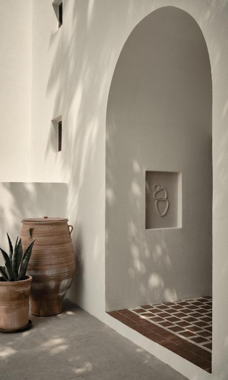 a hallway with a vase and a wall with an arch at Parilio, a Member of Design Hotels in Naousa