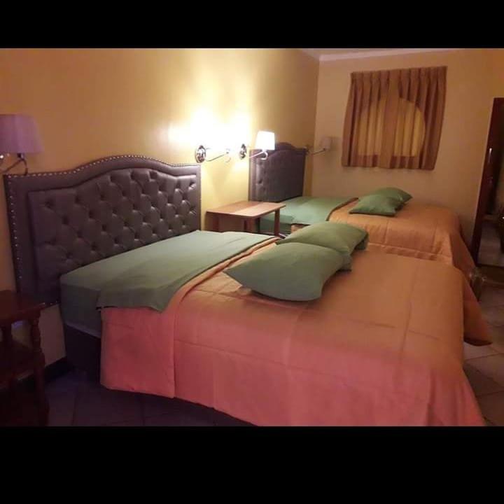 a hotel room with two beds and a table at HOSPEDAJE KAROL in Ayacucho