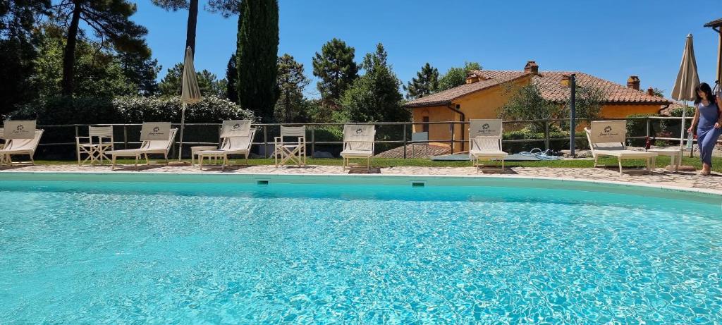 una grande piscina con sedie e una casa di Il Nido a Gambassi