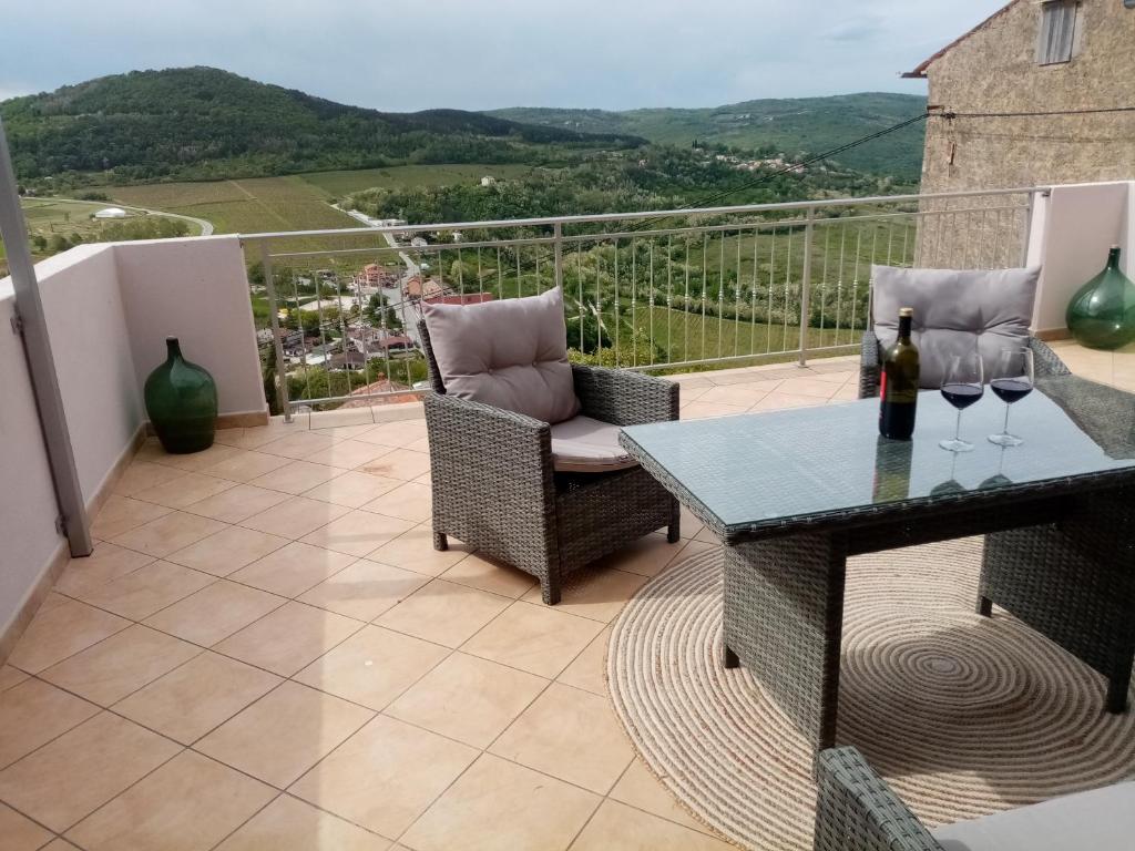 a balcony with a table and chairs with wine glasses at Studio apartman Bel Vedere in Motovun