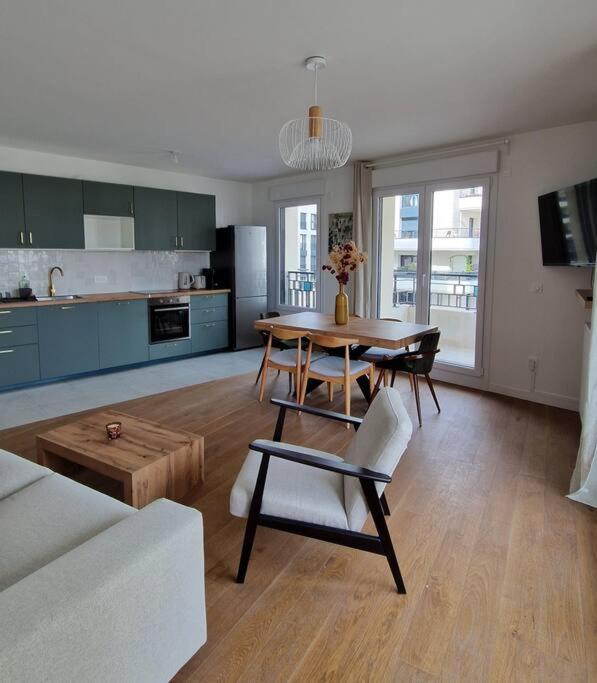 un salon avec une table et une cuisine dans l'établissement Chic & Spacious 3-Bedroom with balcony, à Saint-Ouen