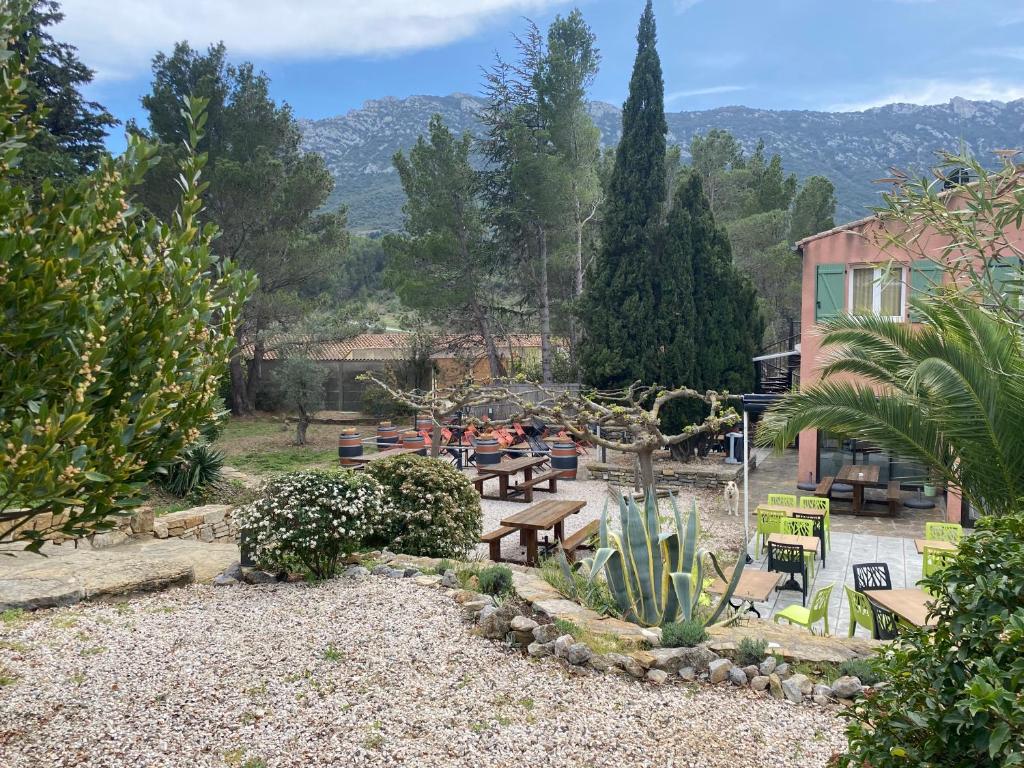 einen Garten mit Picknicktischen und Bänken und ein Gebäude in der Unterkunft Auberge la Table du Curé in Cucugnan