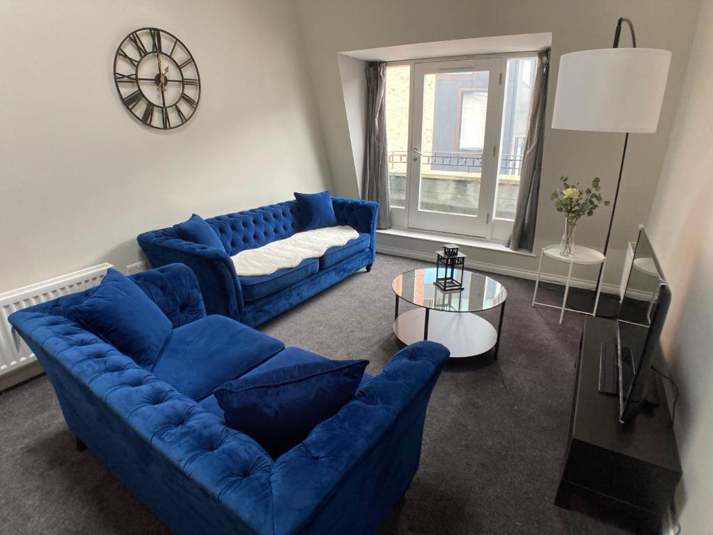 a living room with two blue couches and a table at Edward St Apartments in Belfast